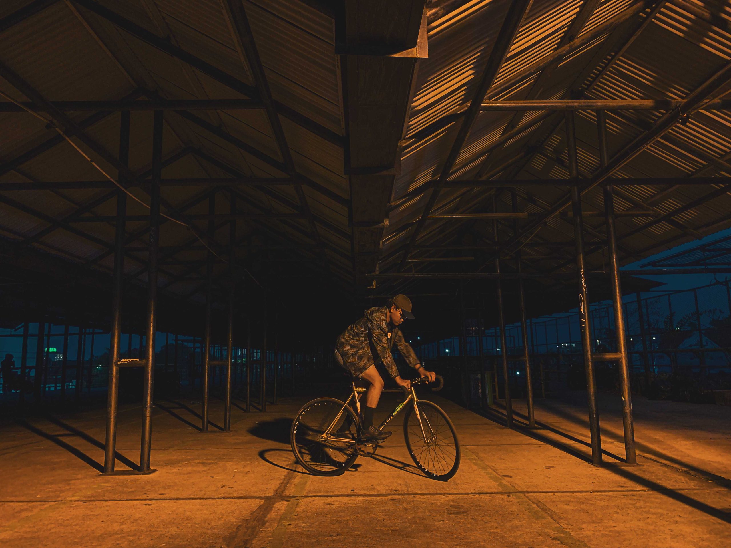 pesepeda urban di tempat parkir abu bakar ali yogyakarta dengan lampu kuning temaram dengan background gelap sedang trackstand