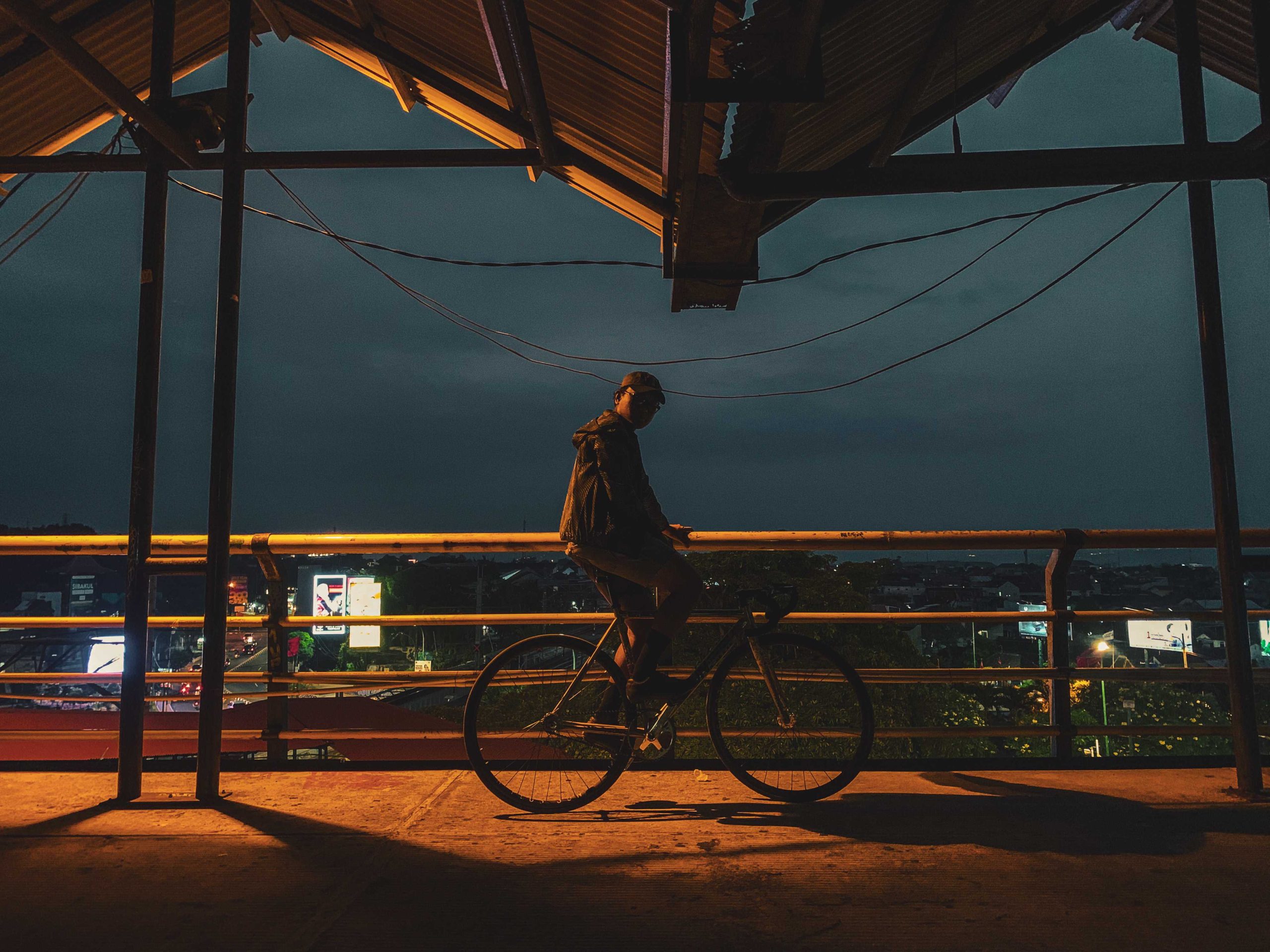 fixed gear cyclist sedang berada di tepi parking lot abu bakar ali melihat keadaan sekitar di tengah kota dengan cahaya city light yang memukau